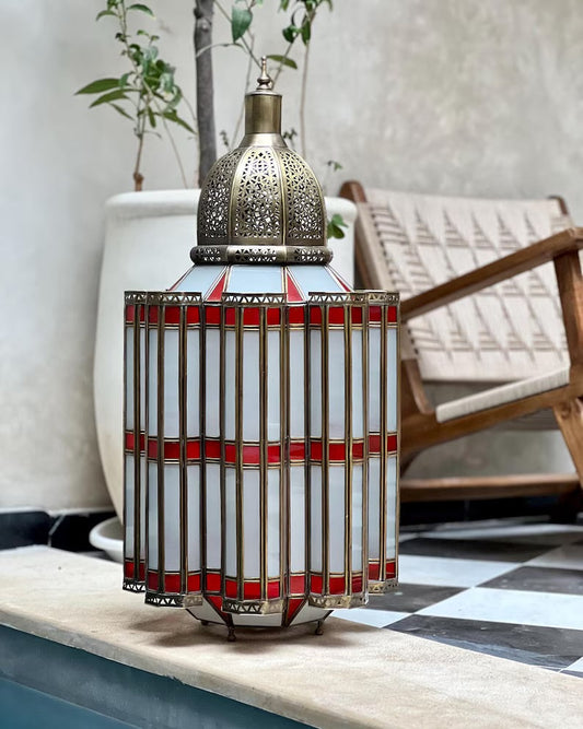 Decorative lantern with red accents on a table by a poolside