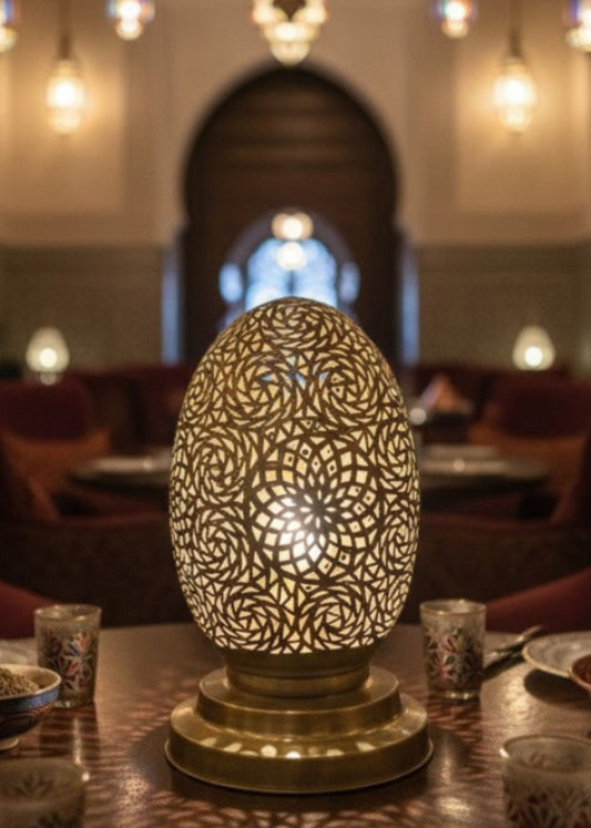 A handmade Moroccan egg-shaped lamp made of polished brass with intricate geometric hand-punched patterns.
