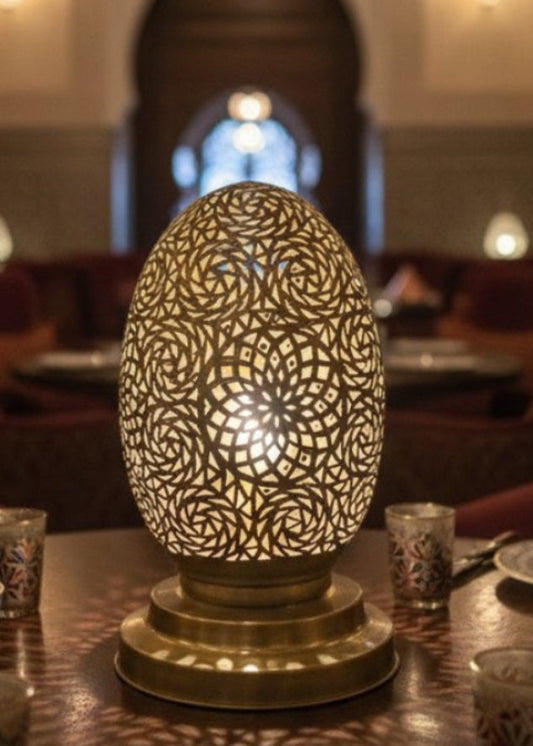 A handmade Moroccan egg-shaped lamp made of polished brass with intricate geometric hand-punched patterns.