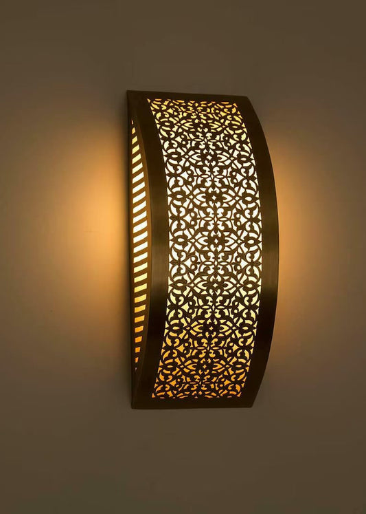 Close-up of a hand-pierced Moroccan brass lamp showing the intricate geometric patterns and warm light diffusion.