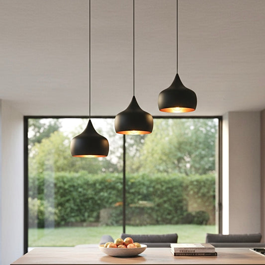 Three handmade modern dome pendant lights with matte black exterior and gold brass interior hanging over a marble kitchen island.