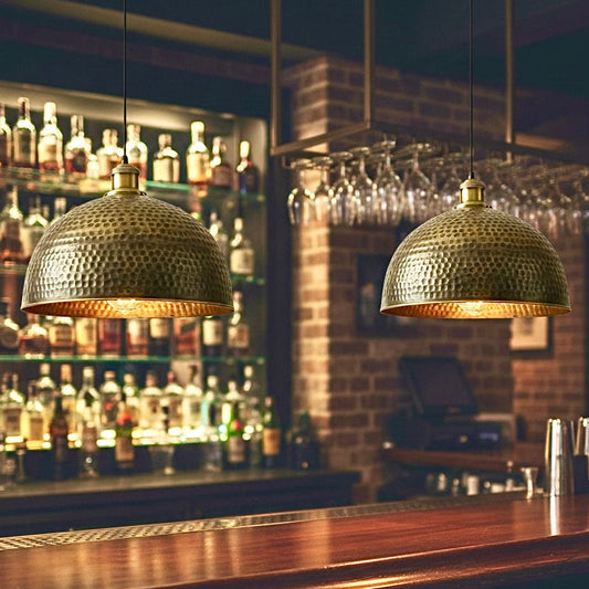 Elegant bronze finished brass lamps hanging over a dark wood bar counter, available for global distribution.