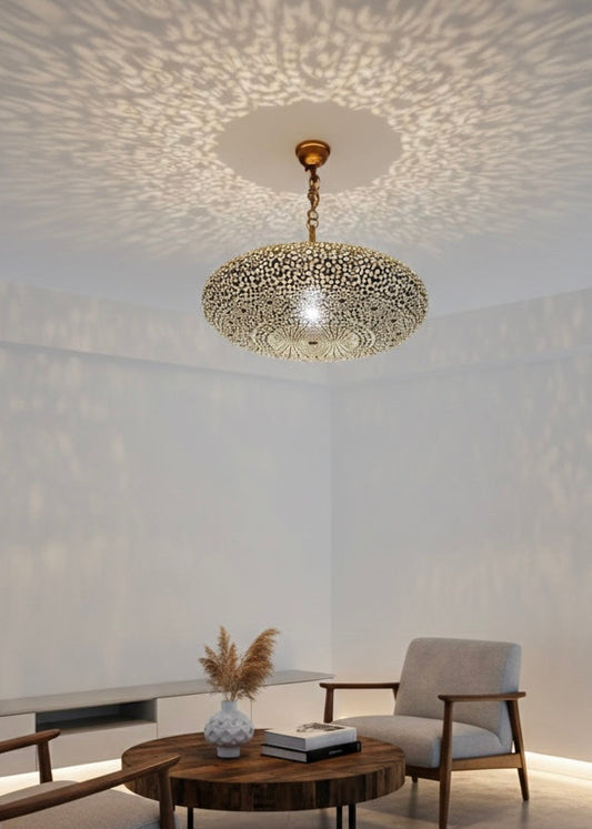 Handmade Moroccan brass pendant light hanging in a modern living room, casting intricate geometric shadows on the ceiling and walls.
