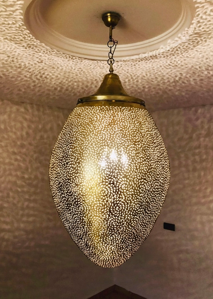 Detailed view of a hanging Moroccan brass lamp, showcasing intricate pierced patterns and warm lighting.