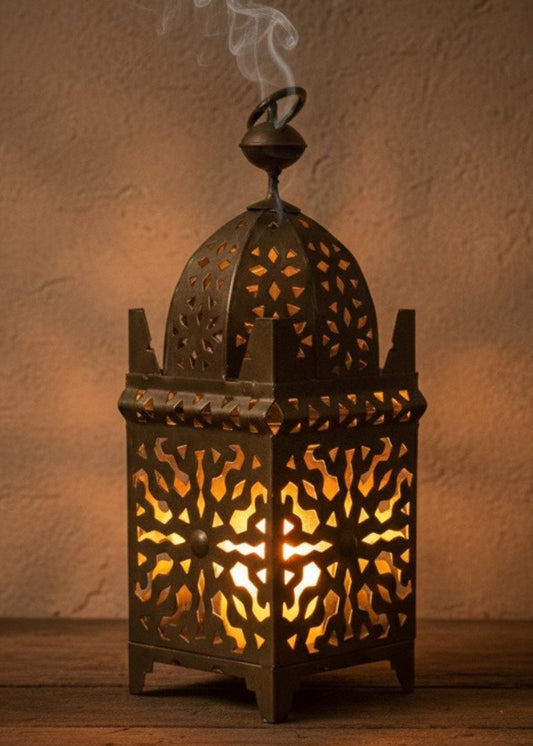 Traditional Moroccan metal lantern with warm light on a white wooden table.
