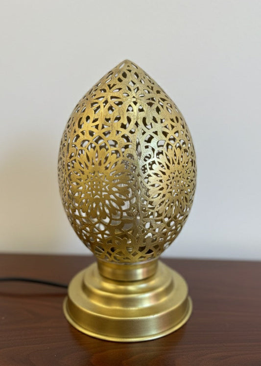 Several teardrop-shaped Moroccan lamps lighting up wooden tables in a cosy, dimly lit restaurant setting.