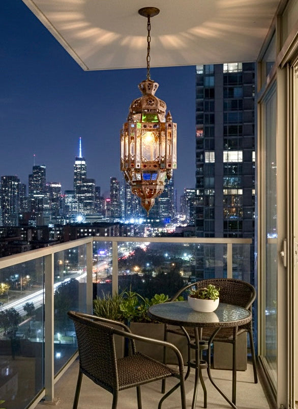 Moroccan glass pendant lamp illuminating a modern high-rise balcony at night, creating warm patterned shadows against the ceiling.