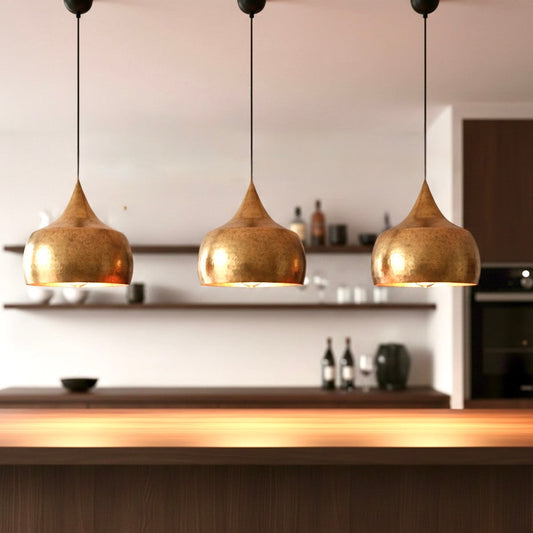 Set of three industrial-style brass pendant lights installed over a wooden kitchen counter.