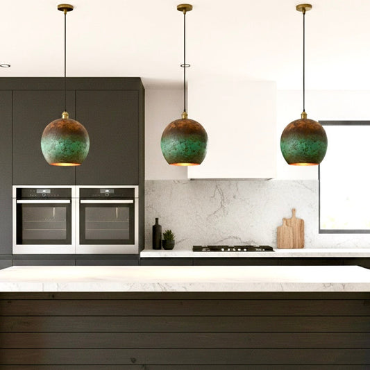 Three rustic Moroccan-style pendant lights with green oxidation hanging over a contemporary marble kitchen island.
