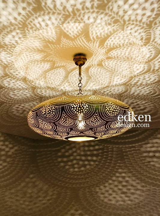 Close-up of a handmade Moroccan pendant light in gold brass with intricate perforated patterns.