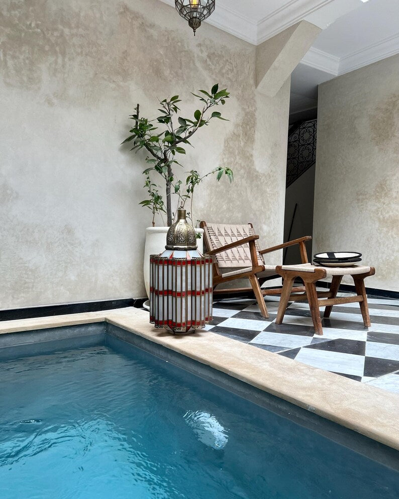 Indoor pool area with wooden chairs, a table, and decorative elements.