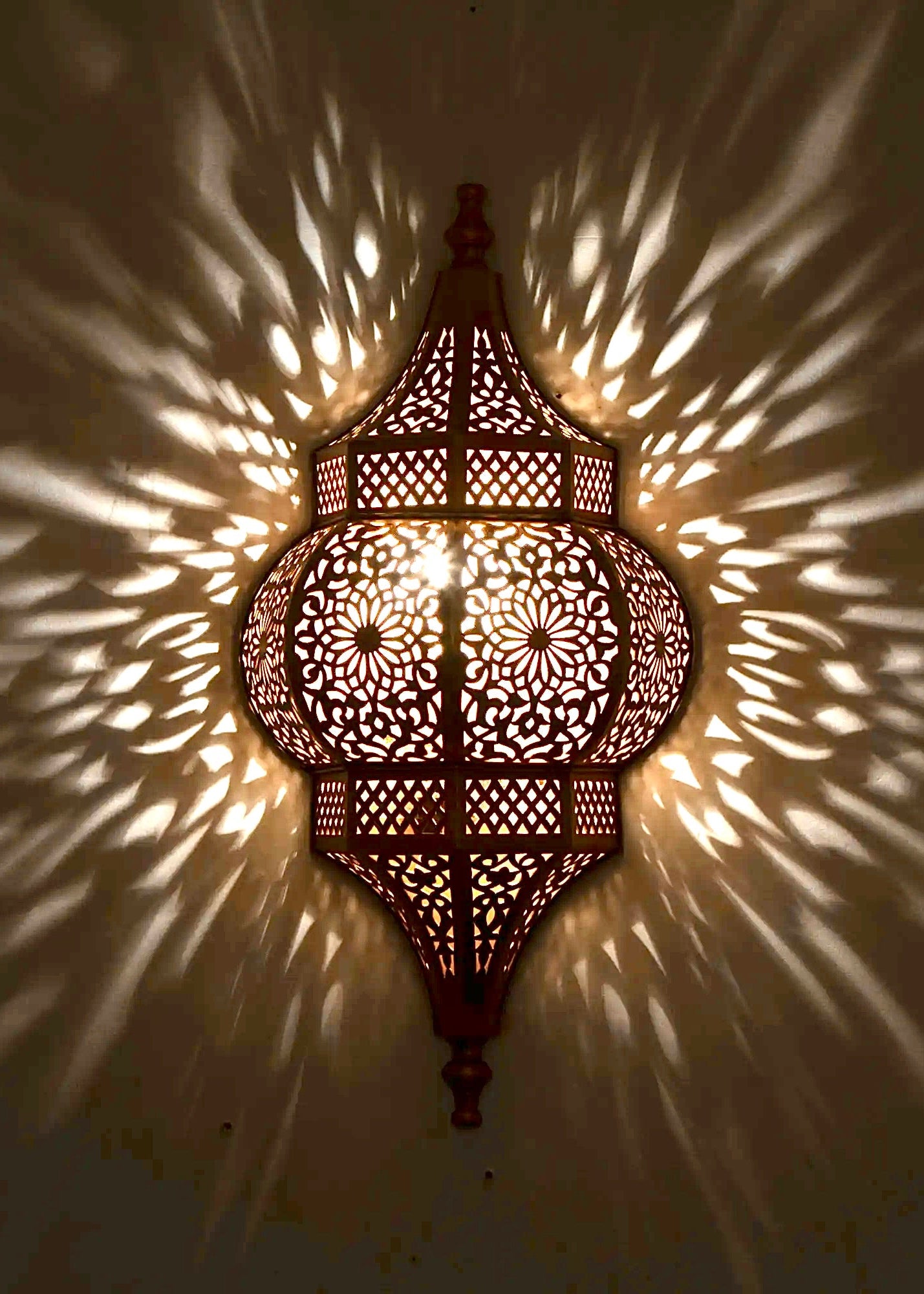 Close-up of the shadow pattern created by a Moroccan handmade brass wall lamp, showing the high-quality craftsmanship and light diffusion.