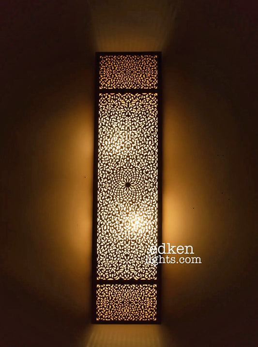 Front view of handmade Moroccan brass wall lamp with geometric cut-out design and warm ambient light