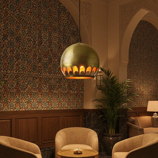 Intricate arch-shaped cutouts on the rim of a brass dome ceiling light, highlighting the warm interior glow and handmade details.