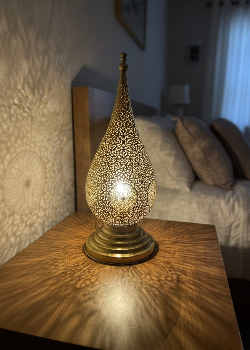 Warm ambient lighting from a Moroccan brass table lamp for a boho-chic interior atmosphere.