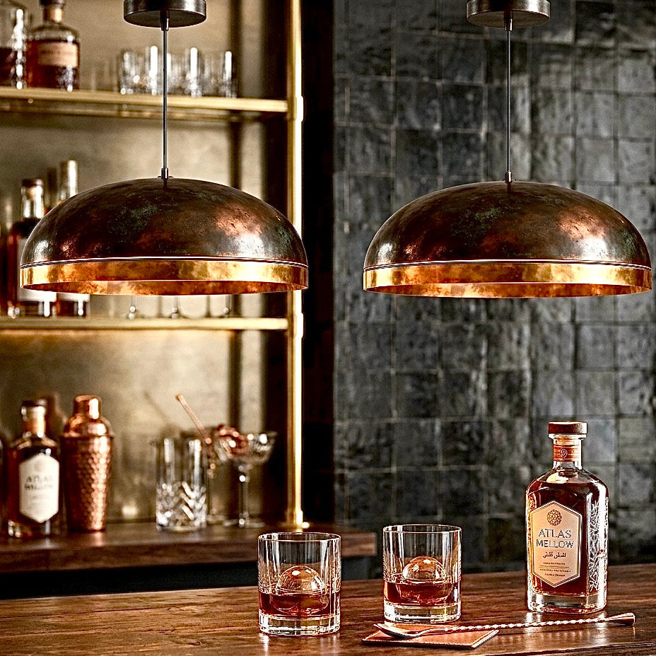 Industrial style antique brass dome lamps lighting up a sophisticated home bar area with dark textures.