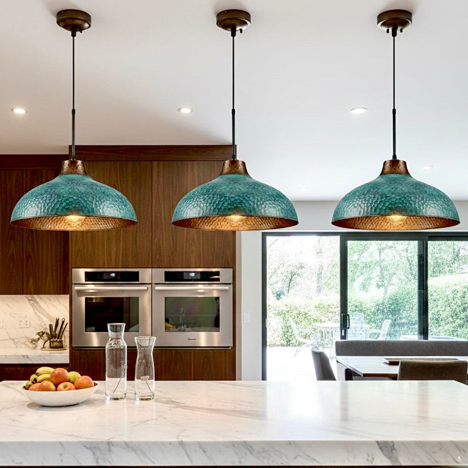 Detailed view of the hand-hammered marks on a green patina brass pendant.