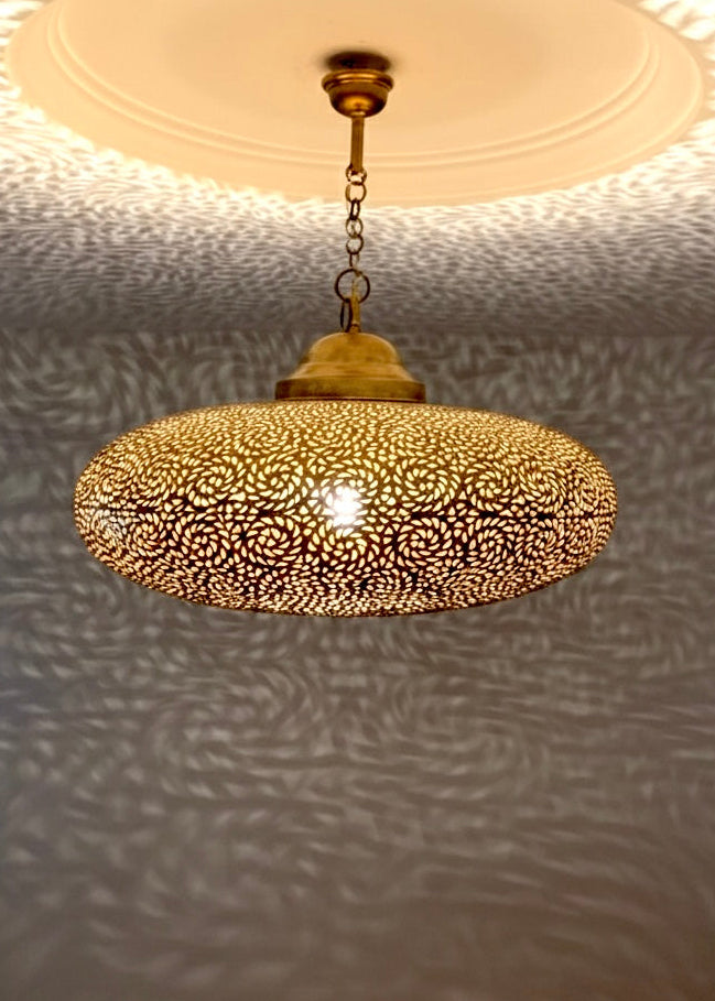 Close-up of an artisanal hand-carved Moroccan brass lamp showing detailed geometric perforations and traditional craftsmanship.