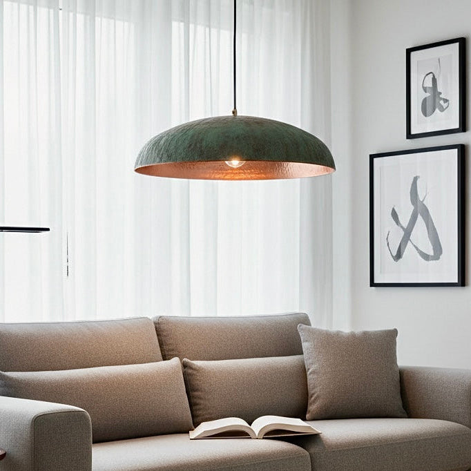 Artisanal copper ceiling light with a unique verdigris finish, providing warm ambient lighting in a creative studio space.
