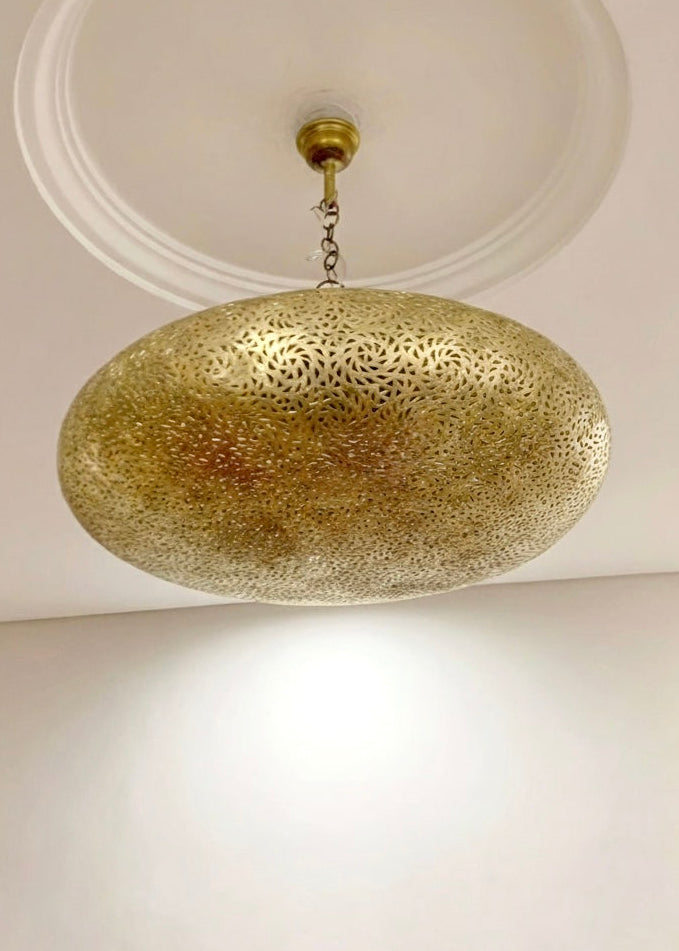 Authentic Moroccan ceiling pendant light made of solid brass with a traditional drop shape, isolated on white.