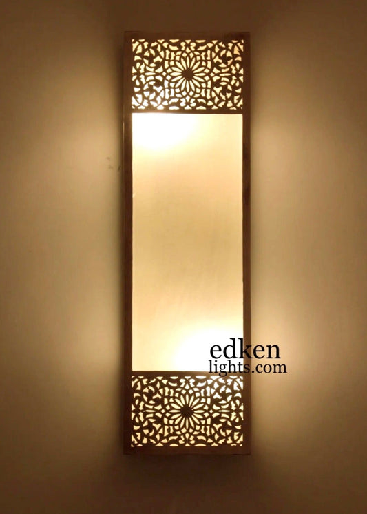 Authentic Moroccan brass wall lamp with intricate hand-punched patterns casting warm geometric shadows.