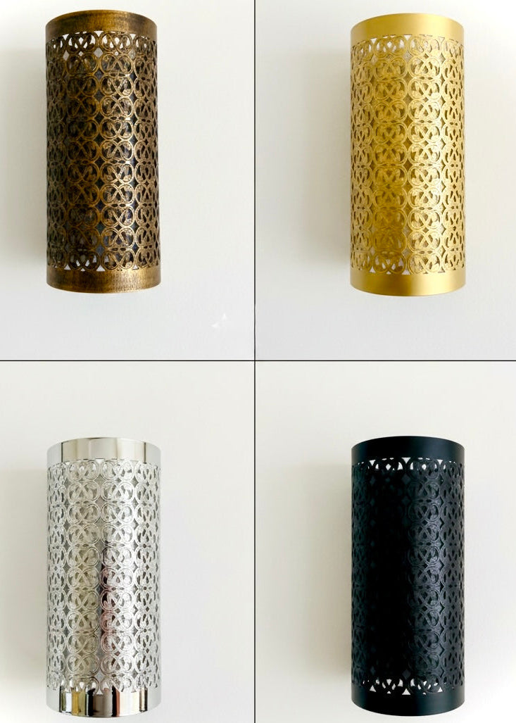 A brass wall sconce used as a bedside lamp, creating a warm and cozy atmosphere with decorative light reflections.