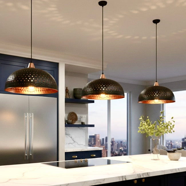Trio of industrial Moroccan style black dome hanging lamps with copper interior over a modern navy blue kitchen island.
