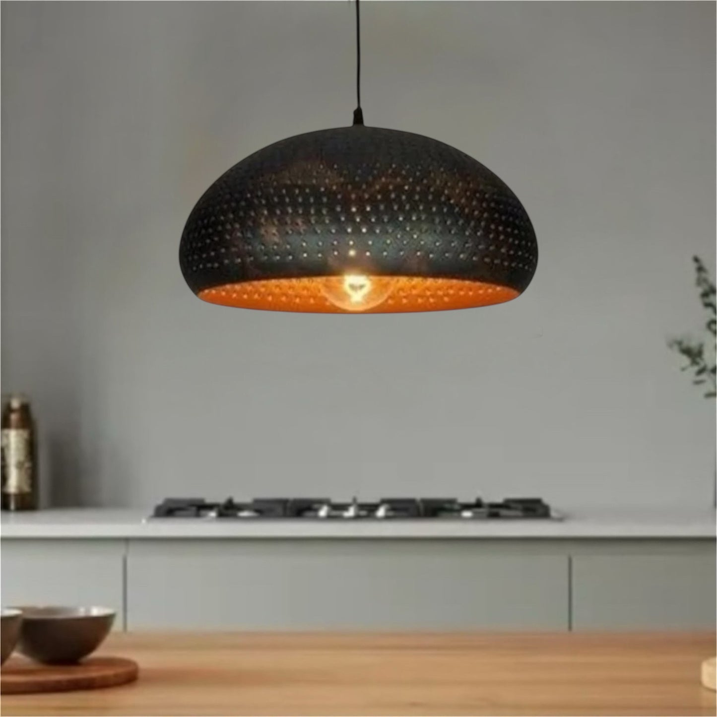 Matte black dome pendant light with perforated metal design and warm light.