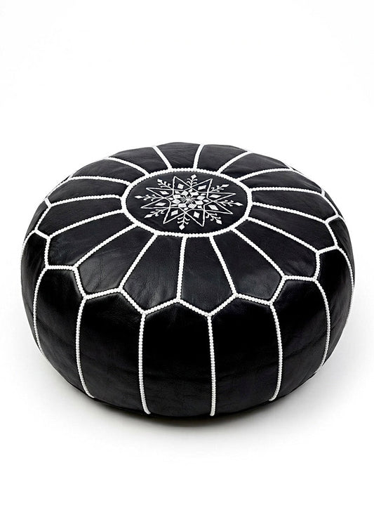Round black leather Moroccan pouf ottoman with traditional white hand-stitched details isolated on white background.⁠