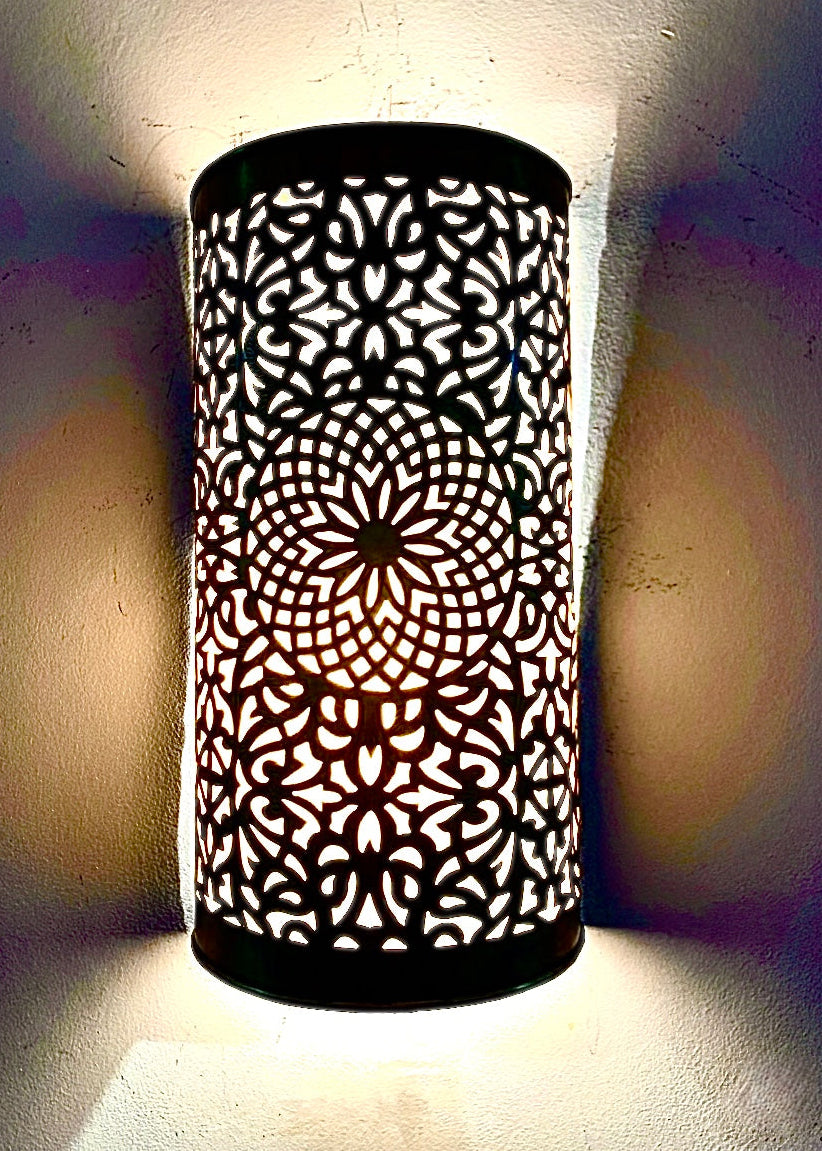 Modern black Moroccan wall sconce creating dramatic light and shadow effects.