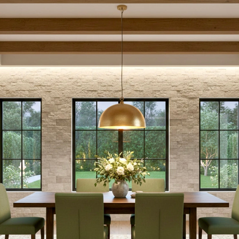 Rustic-modern dining room with a hammered brass dome light and stone wall.