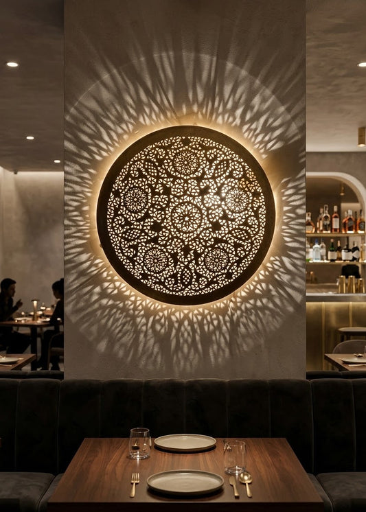 Handmade Moroccan brass wall sconce mounted in a luxury restaurant interior casting warm shadow light pattern.⁠
