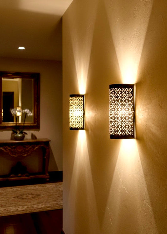Artisanal brass wall lighting fixtures providing a soft golden glow in a luxury home entryway.