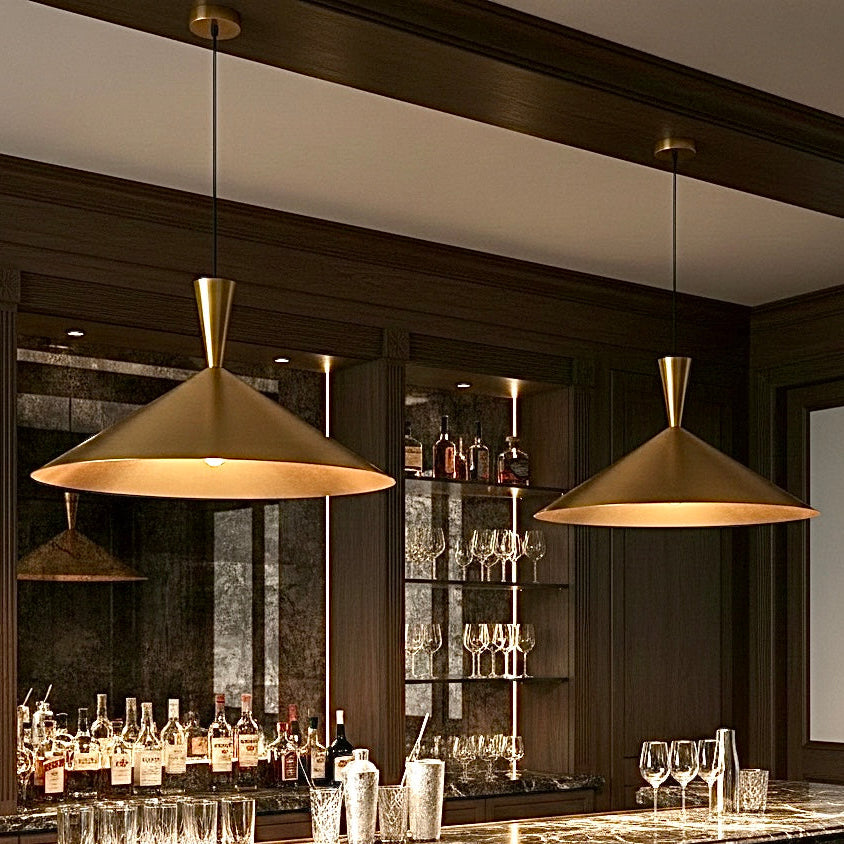 Luxury interior featuring two brushed gold pendant lights illuminating a dark marble bar counter with premium liquor bottles in the background.