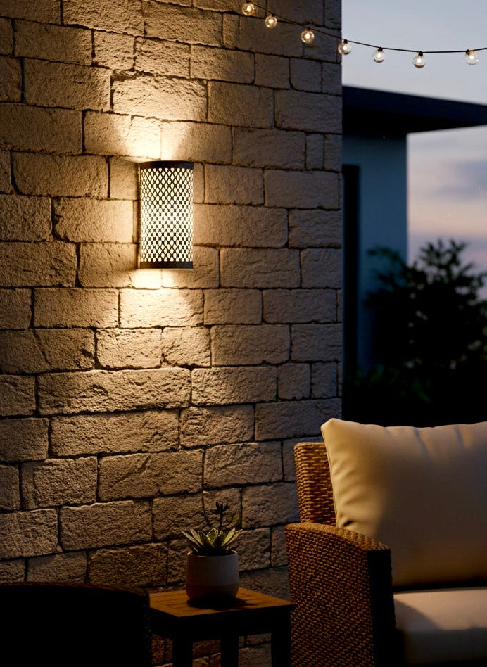 Modern brass Moroccan sconce light providing warm illumination on an outdoor patio wall.