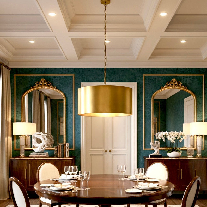 Elegant brass drum pendant providing a warm glow in a sophisticated living room with green velvet furniture.
