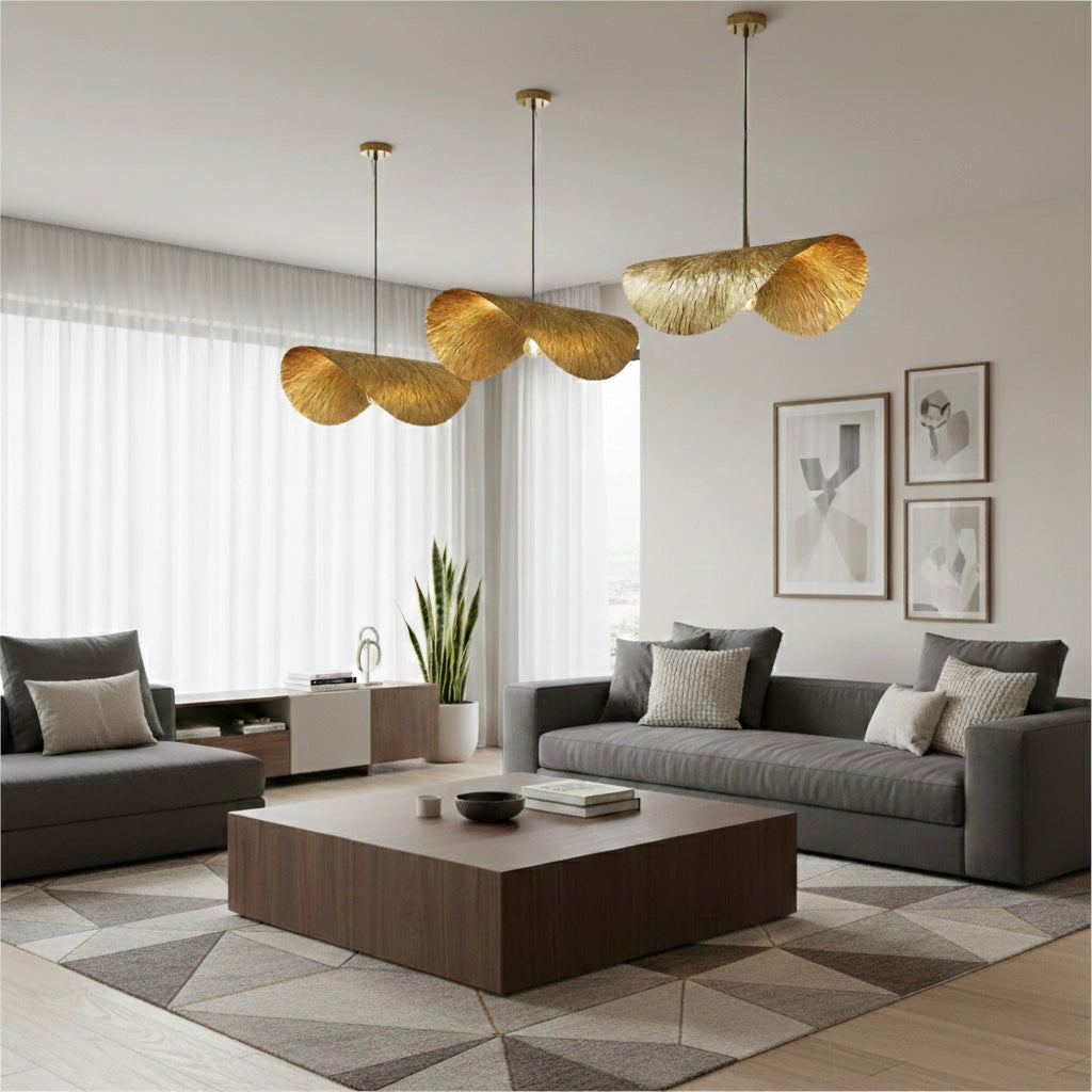 Trio of brass-finished pendant lights in a bright living room with grey sofas and a geometric rug.