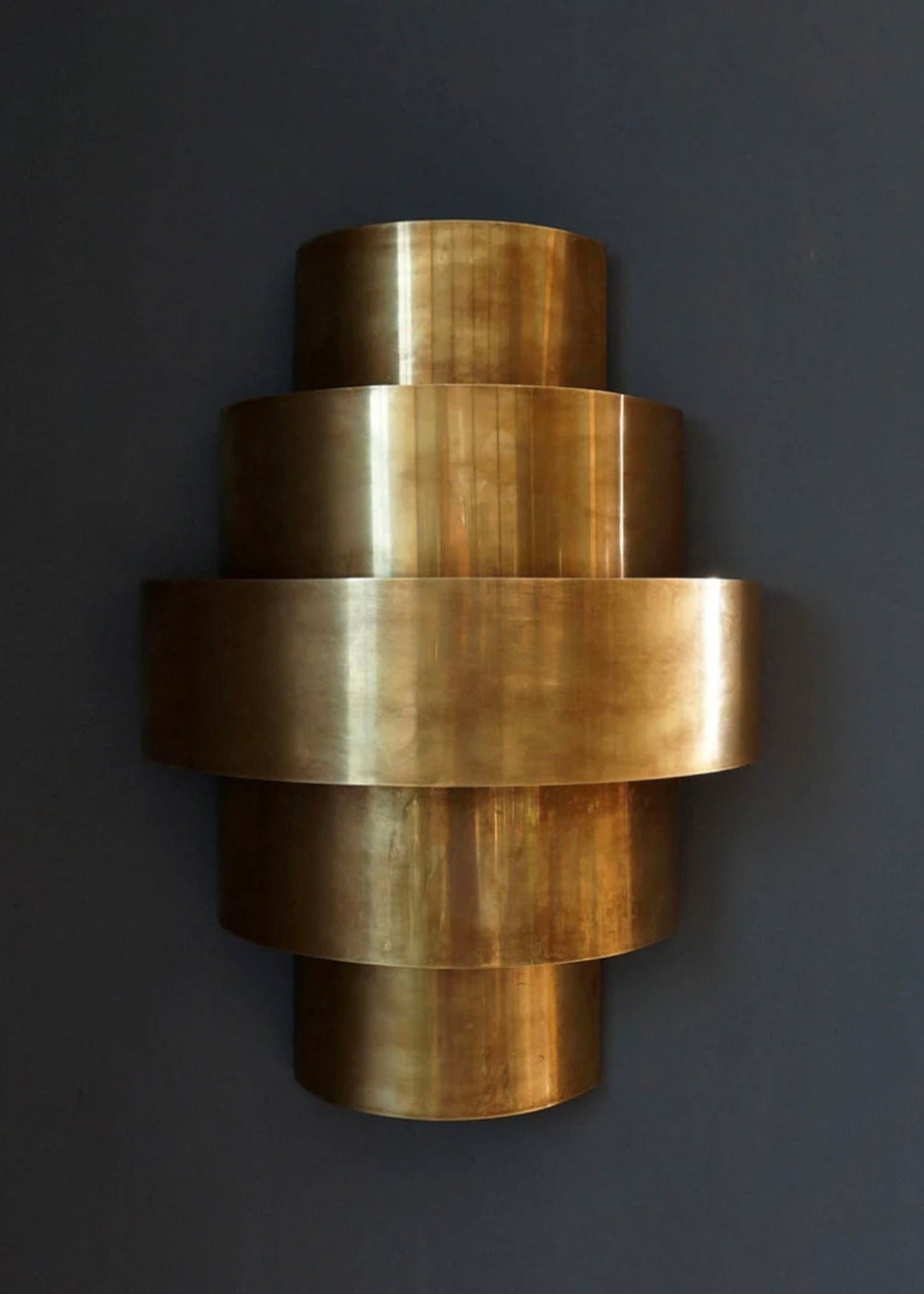 Top angle of a cylindrical brass wall lamp showing the light distribution and layers.