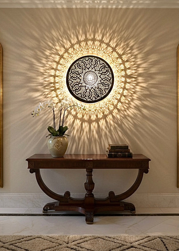 Traditional hand-etched brass wall sconce placed between two mirrors for elegant interior decor.