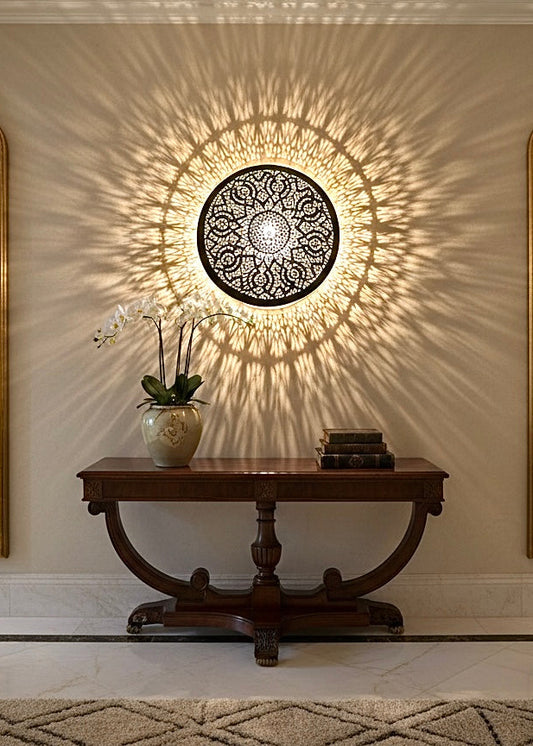 Traditional hand-etched brass wall sconce placed between two mirrors for elegant interior decor.