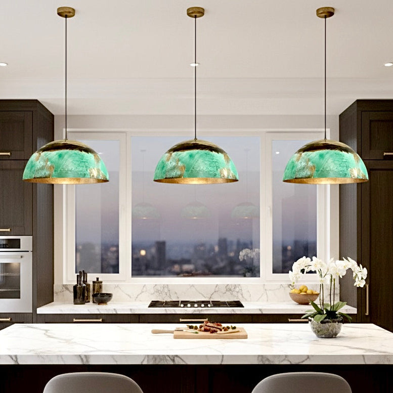 Luxury green oxidation copper dome pendant light hanging over a white kitchen island.