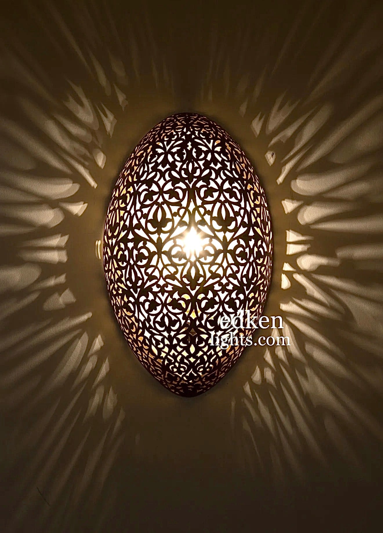 Close-up shot of a hand-etched Moroccan wall lamp showcasing intricate traditional brass patterns and craftsmanship.