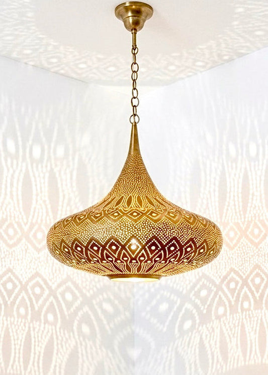 Close-up of a hand-pierced brass lamp reflecting intricate Arabesque shadow patterns on white walls.