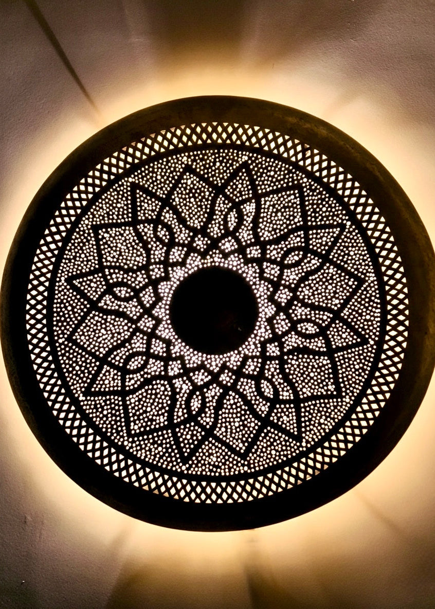 Hand-pierced gold brass flush mount lighting casting magical shadows on ceiling.