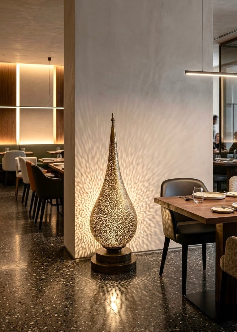 Artisanal Moroccan brass teardrop lamp glowing in a modern luxury restaurant setting, ideal for commercial hospitality interior design lighting projects.