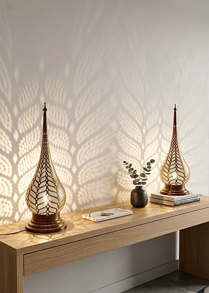 Pair of handmade Moroccan brass desk lamps placed on a wooden console table, creating a warm ambient atmosphere with shadow patterns.