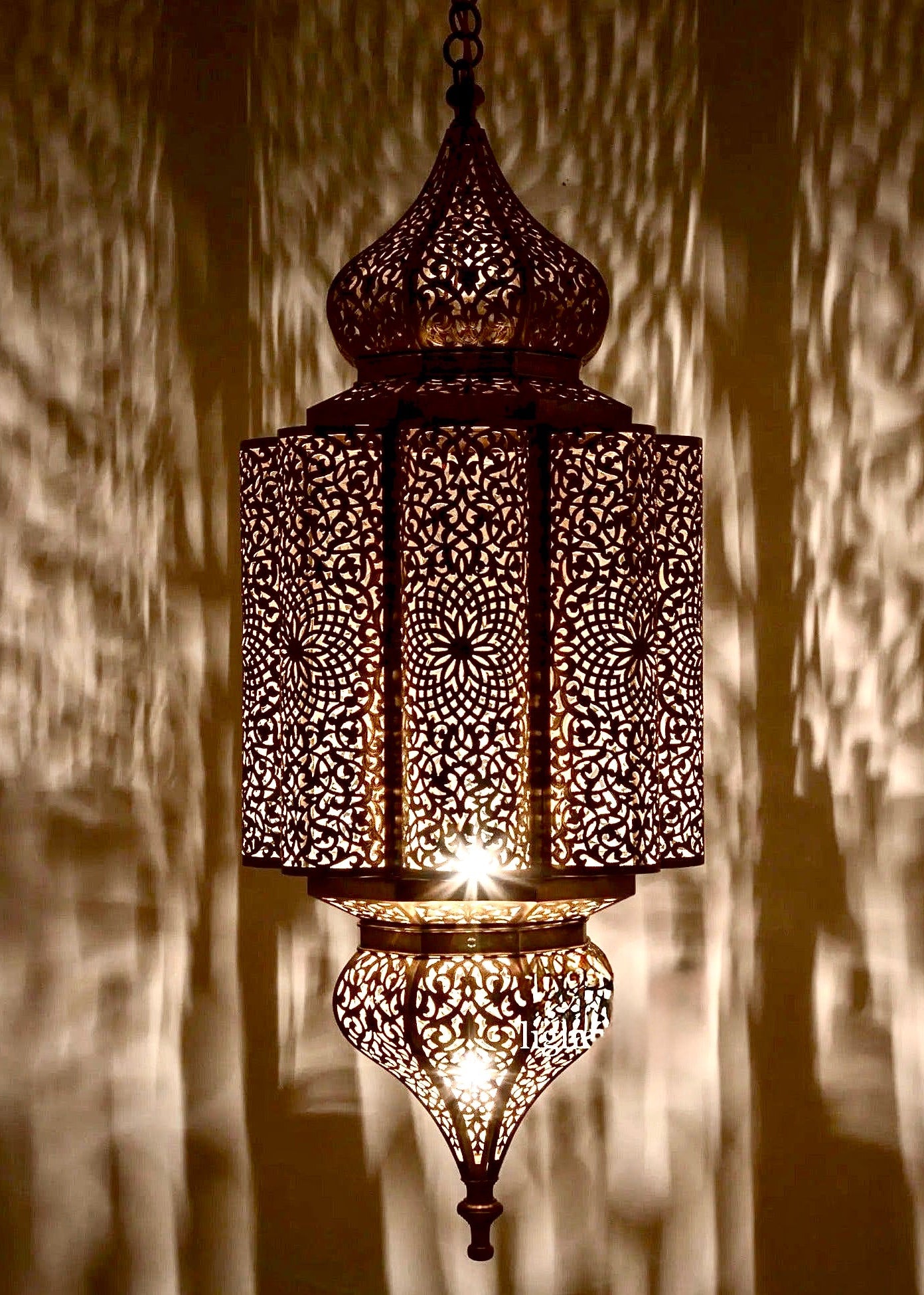 Close-up of a handmade Moroccan ceiling lantern showcasing detailed hand-drilled patterns and authentic brass finish.