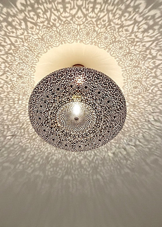 Close-up of a handmade etched brass pendant lamp with a warm gold finish, showcasing traditional Moroccan craftsmanship.