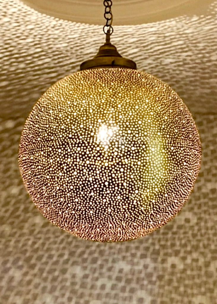 Close-up of a handmade Moroccan brass lamp showing the intricate perforated holes and high-quality artisan craftsmanship.