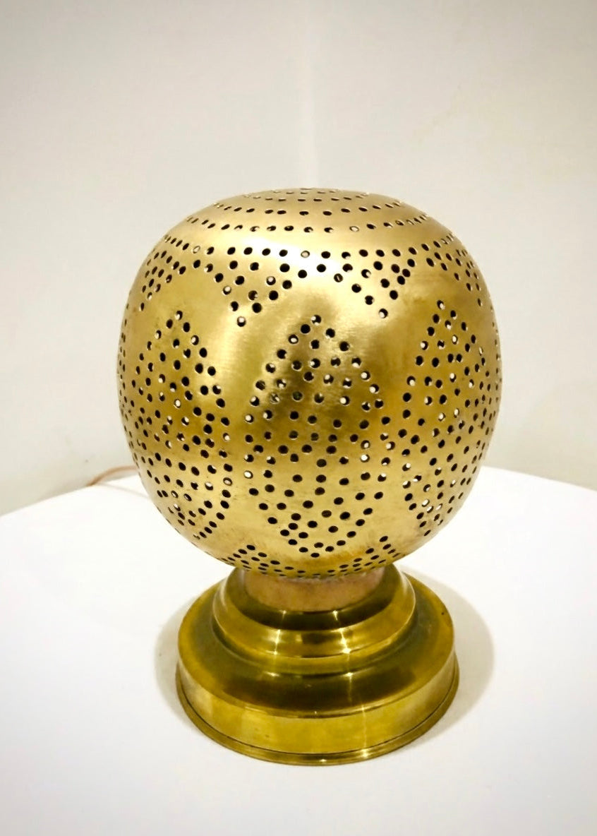 Handmade Moroccan gold brass table lamp featuring a spherical shape with intricate hand-pierced geometric patterns, shown on a white surface.